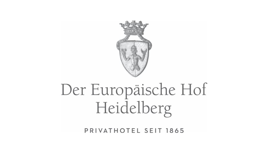Das Logo des „Europäischen Hofs Heidelberg“ zeigt ein Wappenschild mit einem gekrönten Löwen. Der Text darunter lautet „PRIVATHOTEL SEIT 1865“.