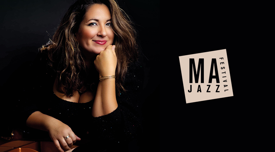 Eine Frau mit welligem braunem Haar und schwarzem Top lächelt und stützt ihr Kinn auf die Hand. Neben ihr befindet sich das Logo des MA Jazz Festivals auf schwarzem Hintergrund.